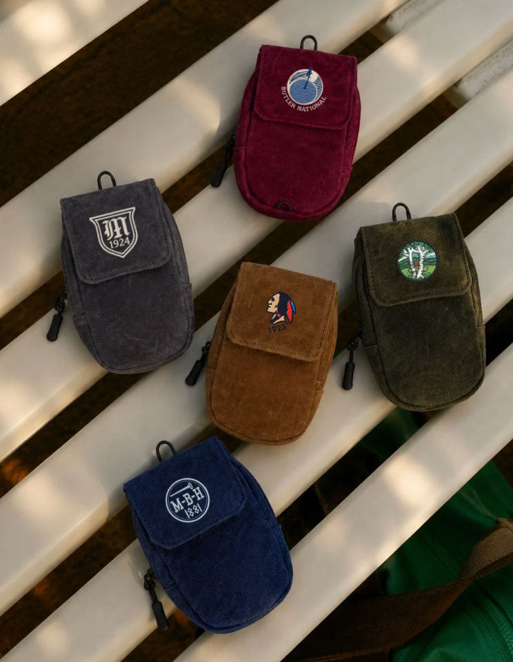 Five small pouches in different colors with embroidered logos on a wooden surface.