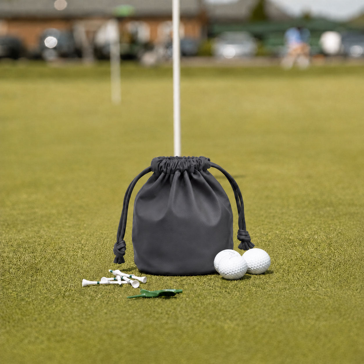 Gray leather golf valuables pouch with drawstring on putting green